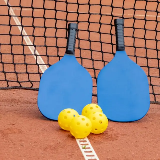 Cover: pickleball paddles and balls on clay